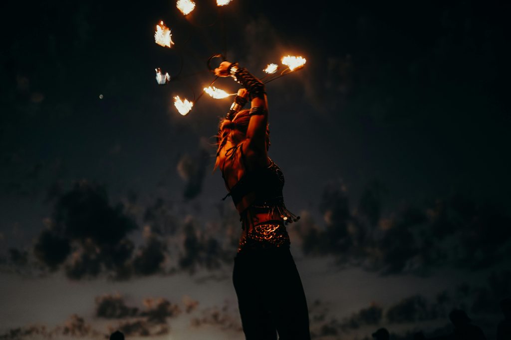 Captivating fire show by a performer on a serene beach at twilight, creating a mesmerizing entertainer's scene.